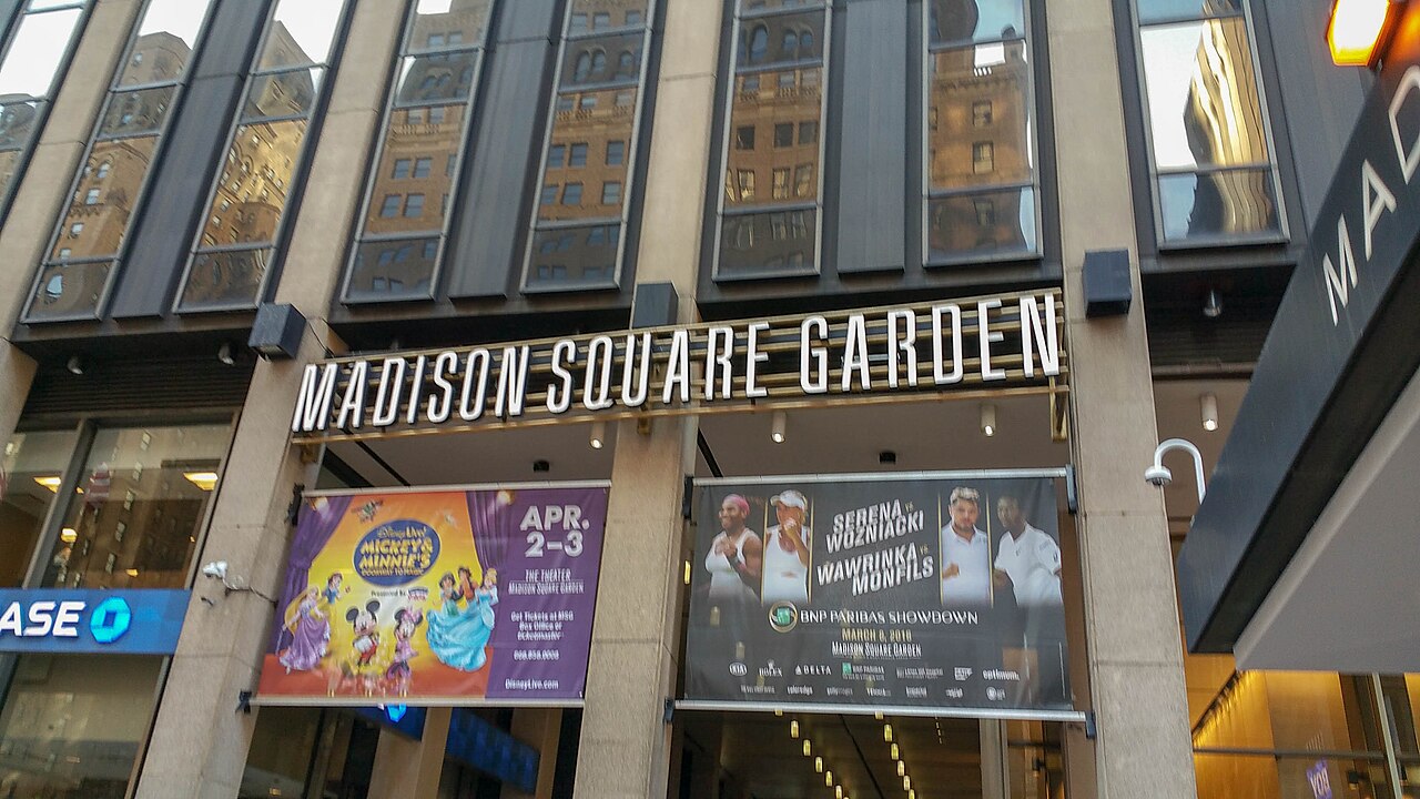 A building entrance with the arena's name in large metal letters above the doors and event posters below.